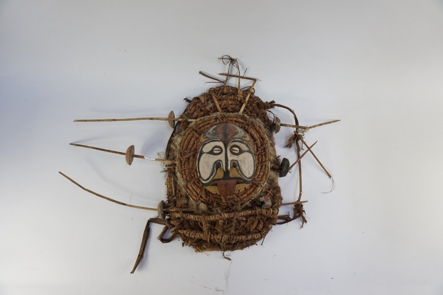 Masque de Papouasie-Nouvelle-Guinée figurant un visage à la langue tirée (culture du fleuve Sepik). Bois sculpté polychrome jaune, blanc, noir et rouge, yeux en cauries, fibres végétales. XXe siècle. Accidents.